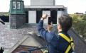 General Manager Kathy Ciesinski photographs the slate tiles from a cherry-picker prior to roof renovations. 